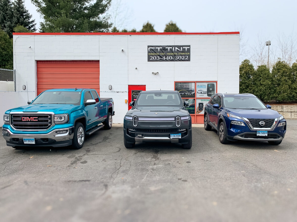 Three vehicles parked outside an auto window tint shop with storefront signage, showcasing vehicle window tint services.