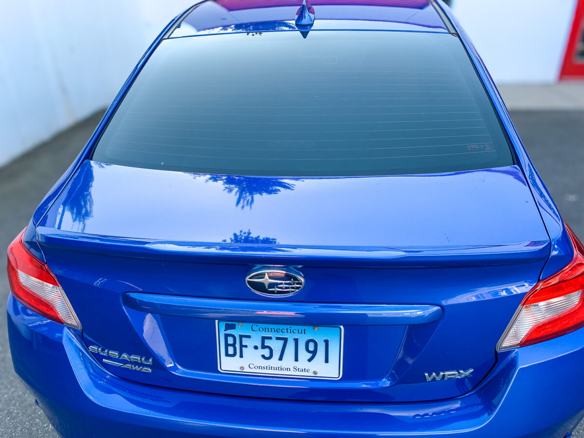 Rear view of a blue sedan with dark window tint on the back glass for added privacy and UV protection