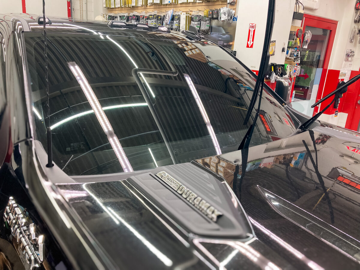 Truck windshield and front side windows with dark window tint inside an auto tint shop for added heat rejection, UV protection, and privacy