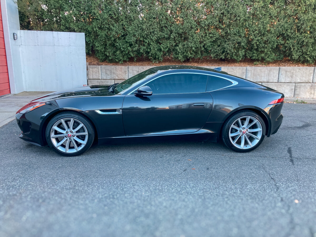 Side view of a dark gray Jaguar coupe with dark window tint for added privacy and UV protection.