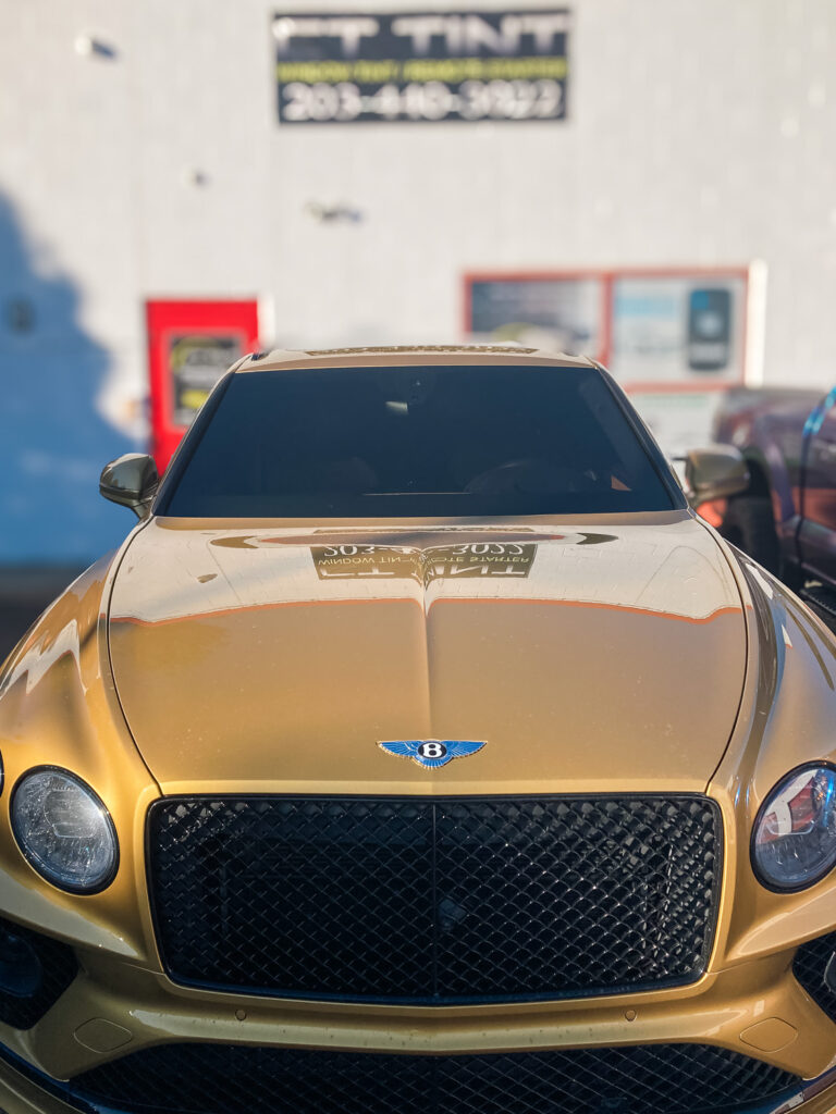 Front view of a gold Bentley with dark tinted windshield and side windows for added privacy and UV protection