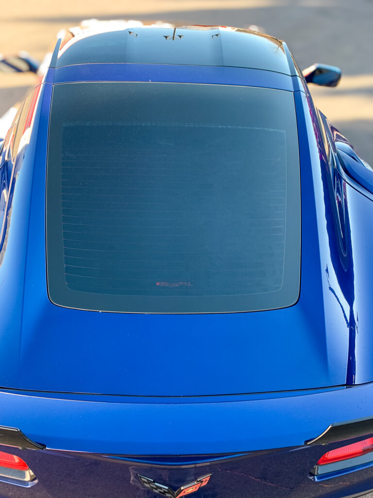 Rear view of a blue sports car with dark tinted back glass for added privacy and UV protection