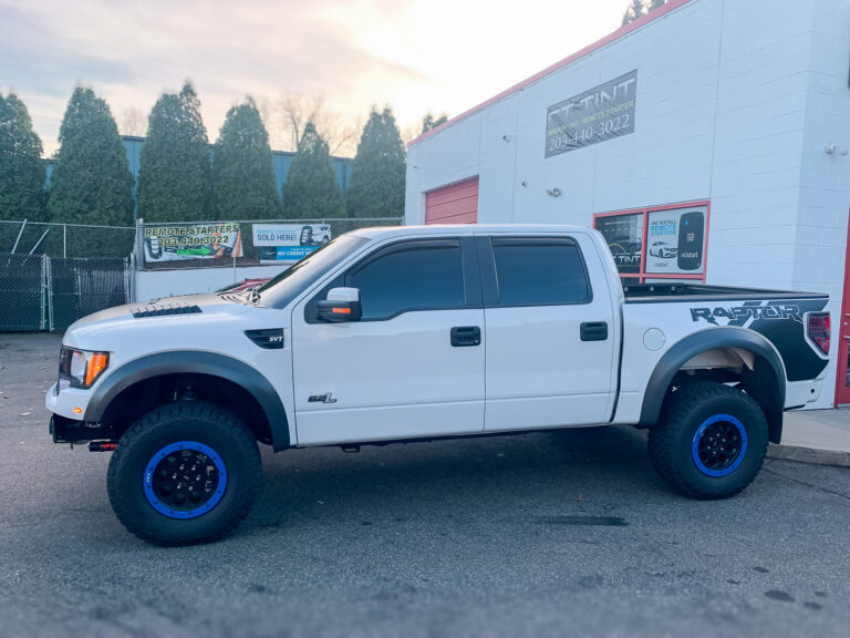 White pickup truck with dark tinted side windows parked outside an auto window tint shop for added privacy and UV protection