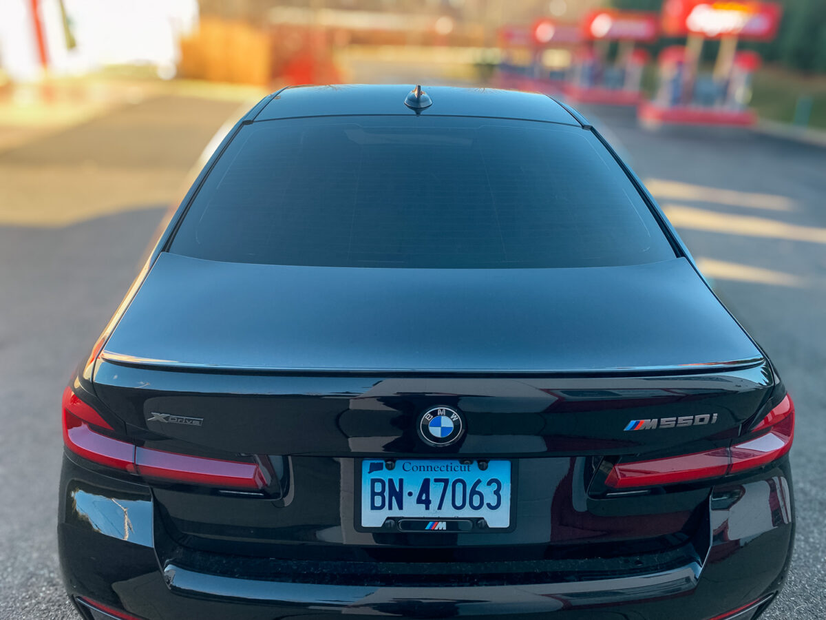 Rear view of a black BMW sedan with dark window tint on the back glass for added privacy and UV protection.